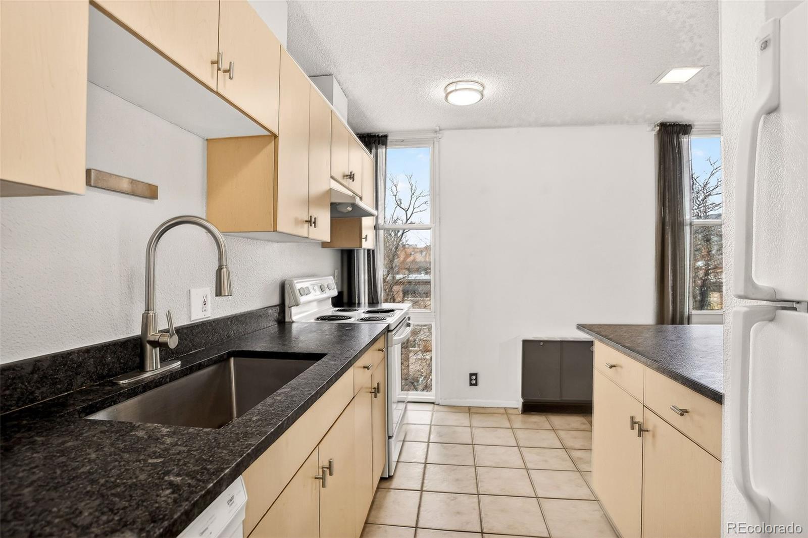 2500 South York Street, Unit 401 Denver, CO 80210 - Photo 12 of 30 a kitchen with granite countertop a sink a stove and a microwave