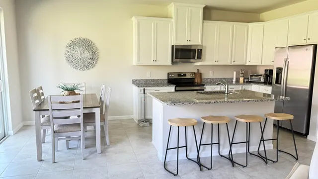 a kitchen with stainless steel appliances granite countertop a table chairs microwave and sink
