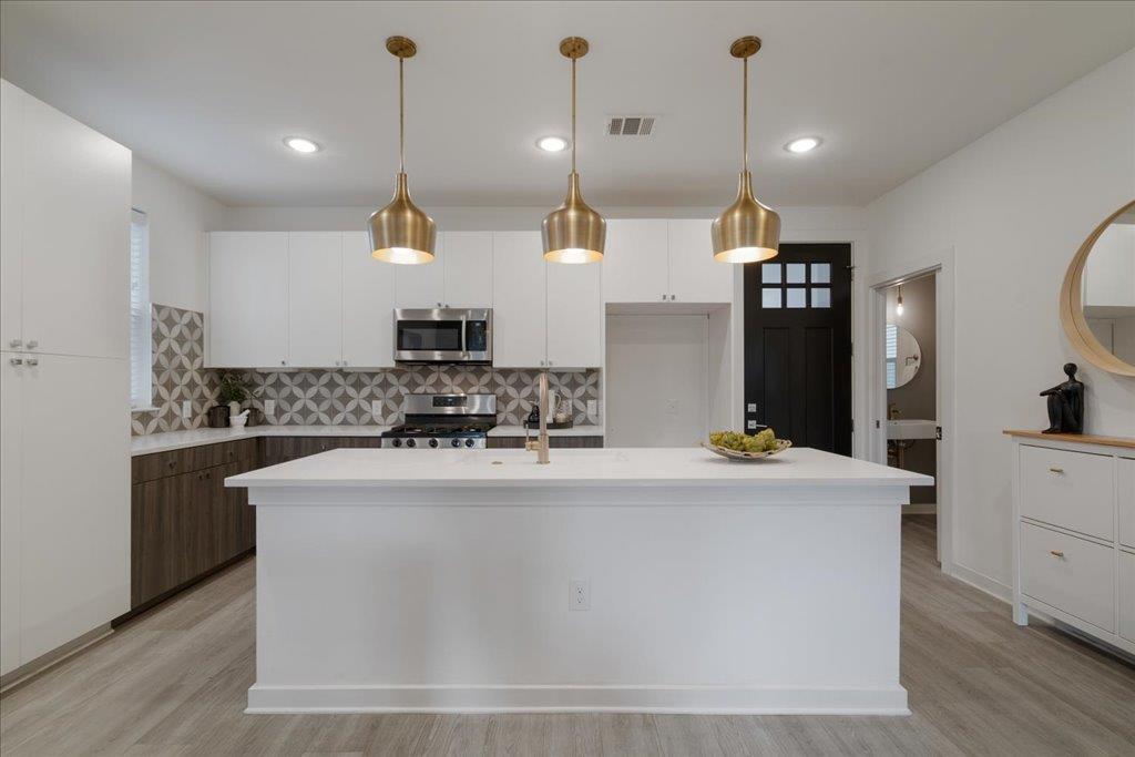 2624 Metcalfe Road, Unit 10 Austin, TX 78741 - Photo 3 of 27 Kitchen featuring white cabinets, pendant lighting, tasteful backsplash, stainless steel appliances, and recessed lighting