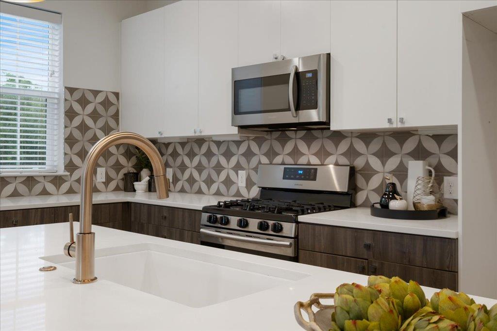 2624 Metcalfe Road, Unit 10 Austin, TX 78741 - Photo 7 of 27 Kitchen with appliances with stainless steel finishes, white cabinets, tasteful backsplash, modern cabinets, and light stone counters