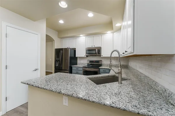 a kitchen with stainless steel appliances granite countertop a sink refrigerator and microwave