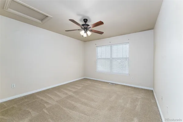 an empty room with a chandelier fan and windows