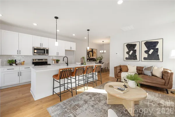 a living room with furniture a rug kitchen view and a chandelier