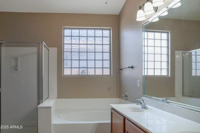 a bathroom with a granite countertop sink a large mirror and a bathtub next to a window