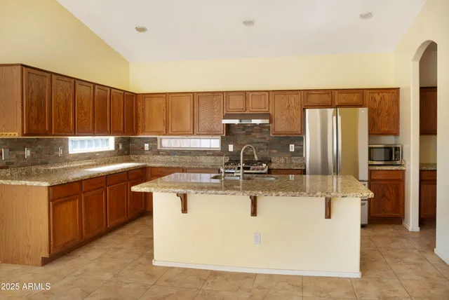 a kitchen with stainless steel appliances granite countertop a sink a stove and a refrigerator