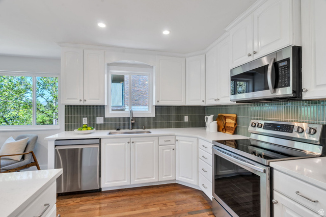3813 North Foothill Drive Provo, UT 84604 - Photo 17 of 71 Kitchen featuring white cabinetry, stainless steel appliances, a tile backsplash, light countertops, and wood-finish flooring