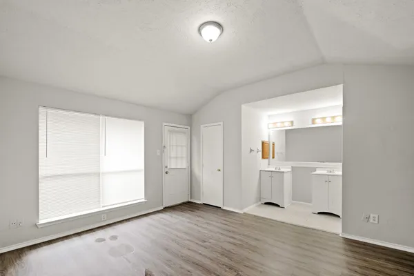an empty room with wooden floor and windows