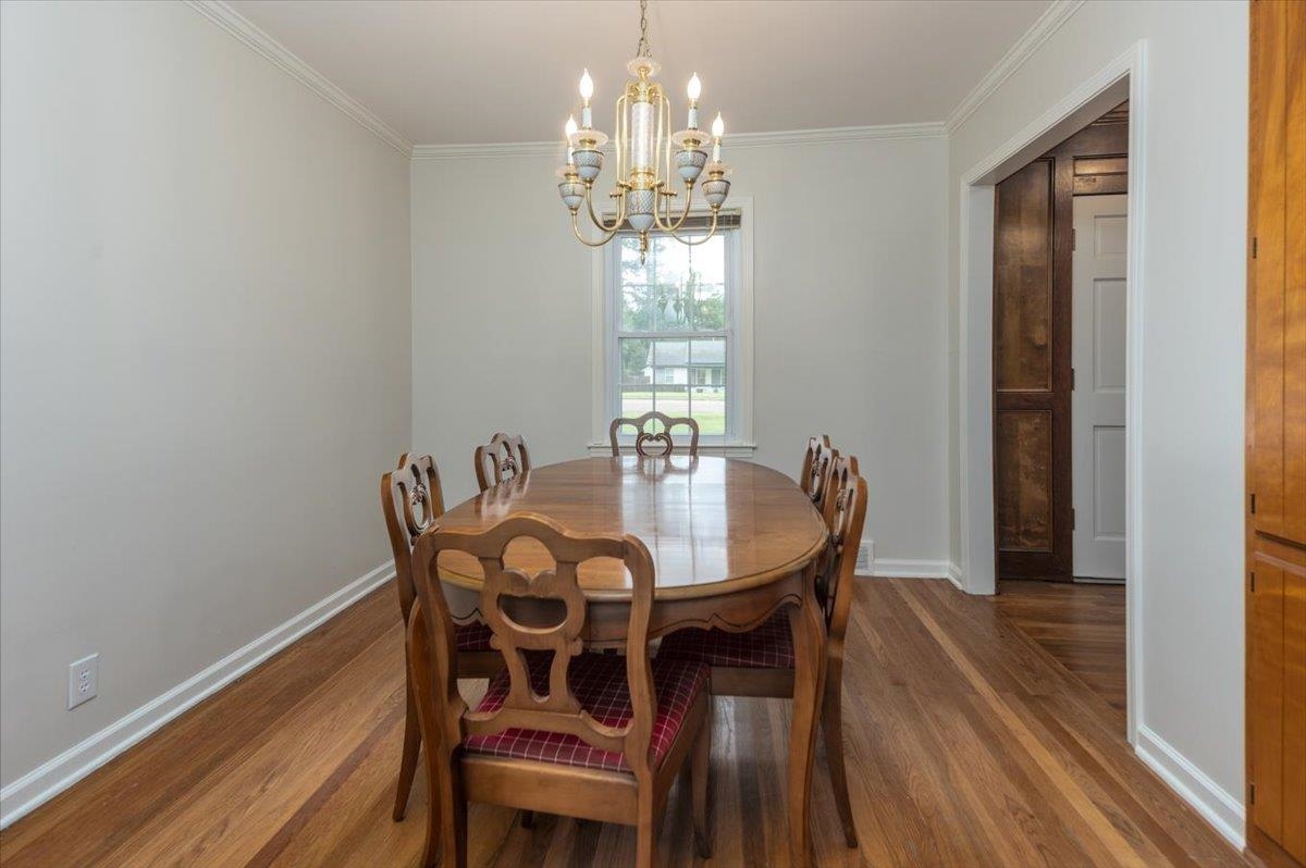 670 Peterson Lake Road Collierville, TN 38017 - Photo 18 of 37 Dining area featuring wood-finish flooring, a window with exterior visibility, crown molding, and a chandelier