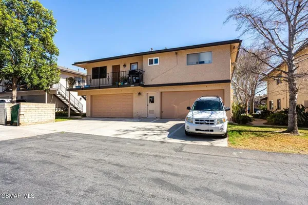 a front view of a house with cars parked