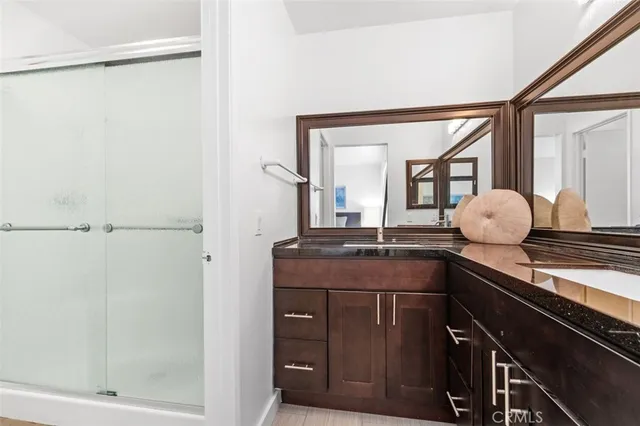 a bathroom with a granite countertop sink a mirror and shower
