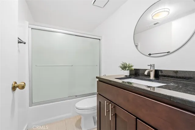 a bathroom with a granite countertop sink mirror vanity and toilet