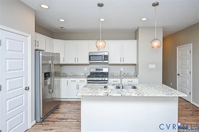 a kitchen with kitchen island granite countertop stainless steel appliances a stove refrigerator and cabinets