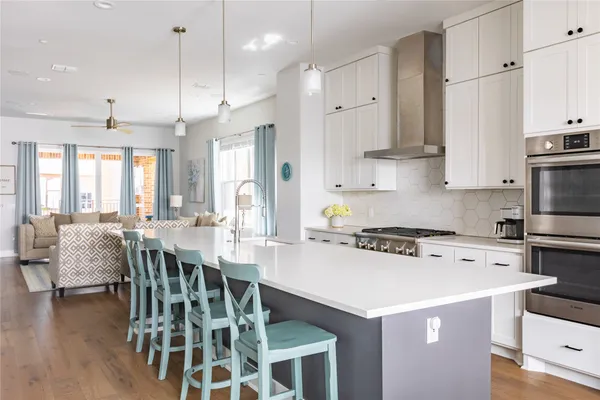 a kitchen with a dining table chairs wooden floor cabinets and stainless steel appliances