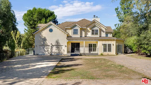 a view of a brick house with a clock tower in middle of a yard