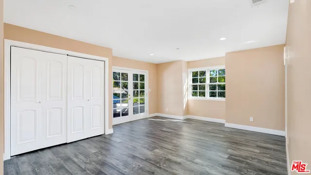 a view of an empty room with wooden floor and a bathroom
