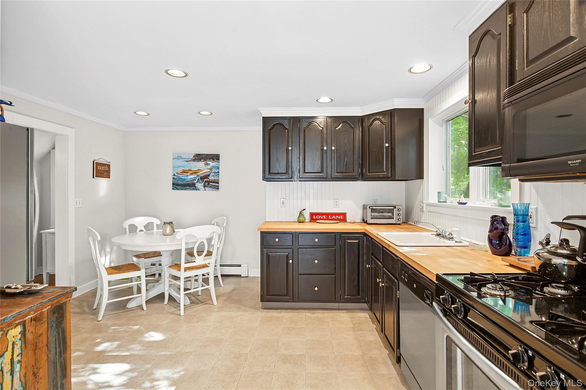 150 Hobart Road Southold, NY 11971 - Photo 4 of 18 a kitchen with stainless steel appliances granite countertop a stove top oven a sink a dining table and chairs with wooden floor