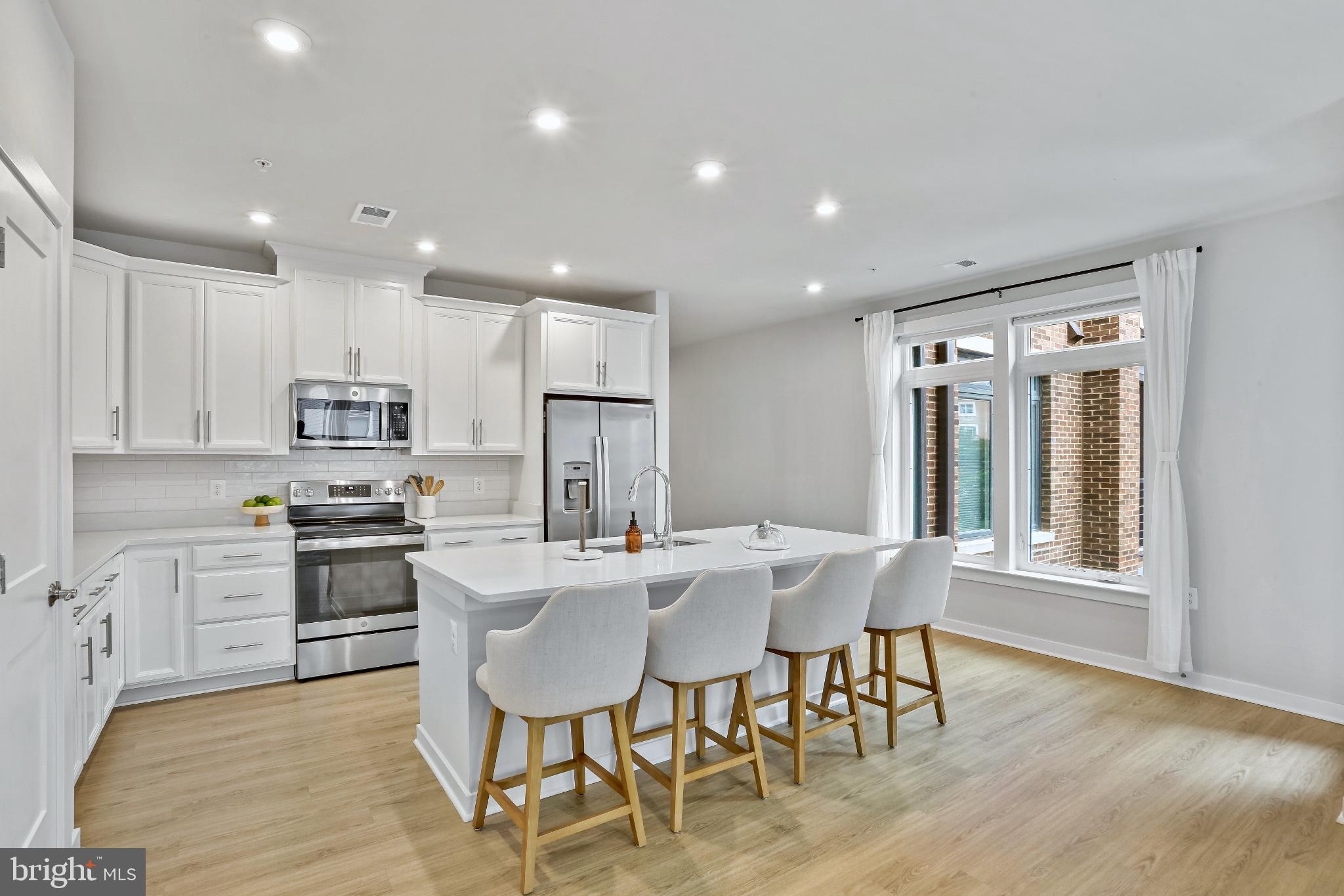 1675 Bandit Loop, Unit 201B Reston, VA 20190 - Photo 5 of 27 a kitchen with stainless steel appliances granite countertop a stove top oven a sink dishwasher a dining table and chairs with wooden floor