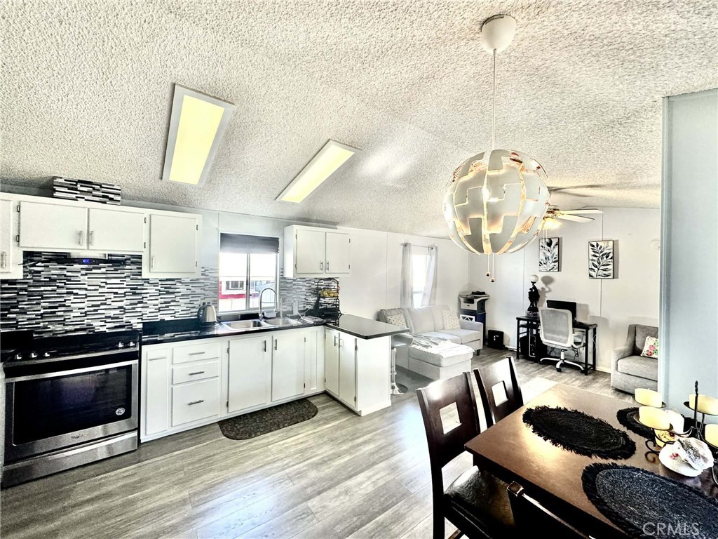 8811 Park Street, Unit 54 Bellflower, CA 90706 - Photo 6 of 13 a kitchen with stainless steel appliances a stove a sink dishwasher and white cabinets with wooden floor