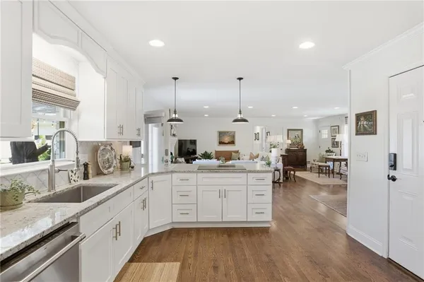 a large white kitchen with a large window a sink and stainless steel appliances