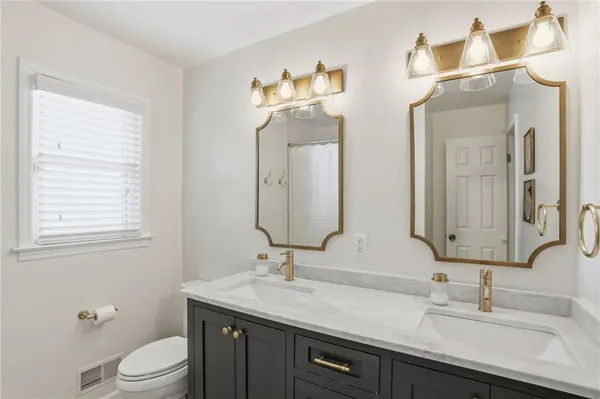 a bathroom with a double vanity sink toilet and a mirror