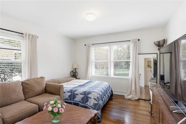 a bedroom with a bed couches and a flat tv screen
