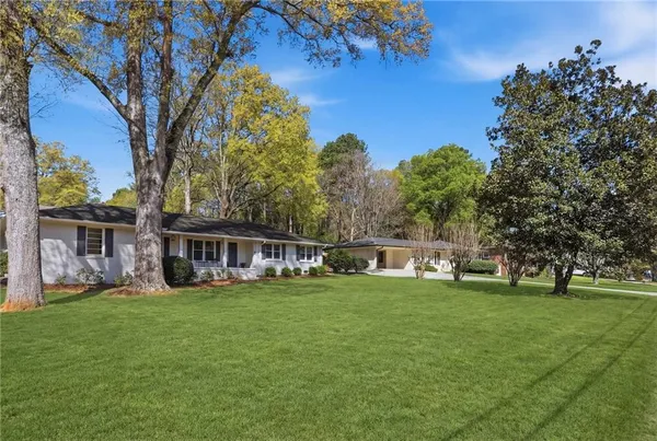 a view of a house with a big yard and large trees