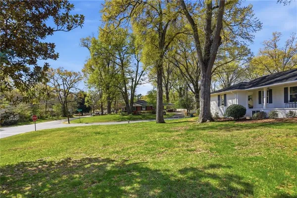 a view of a house with a big yard and large trees