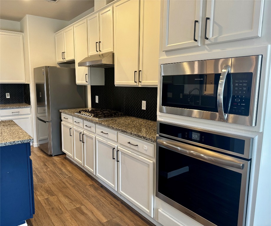 104 Silk Tree Lane Round Rock, TX 78664 - Photo 11 of 29 a kitchen with stainless steel appliances kitchen island granite countertop a stove microwave and refrigerator
