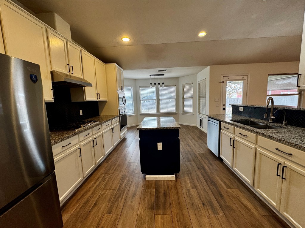 104 Silk Tree Lane Round Rock, TX 78664 - Photo 12 of 29 a large kitchen with stainless steel appliances a large counter top a stove a refrigerator a sink a microwave and wooden floor