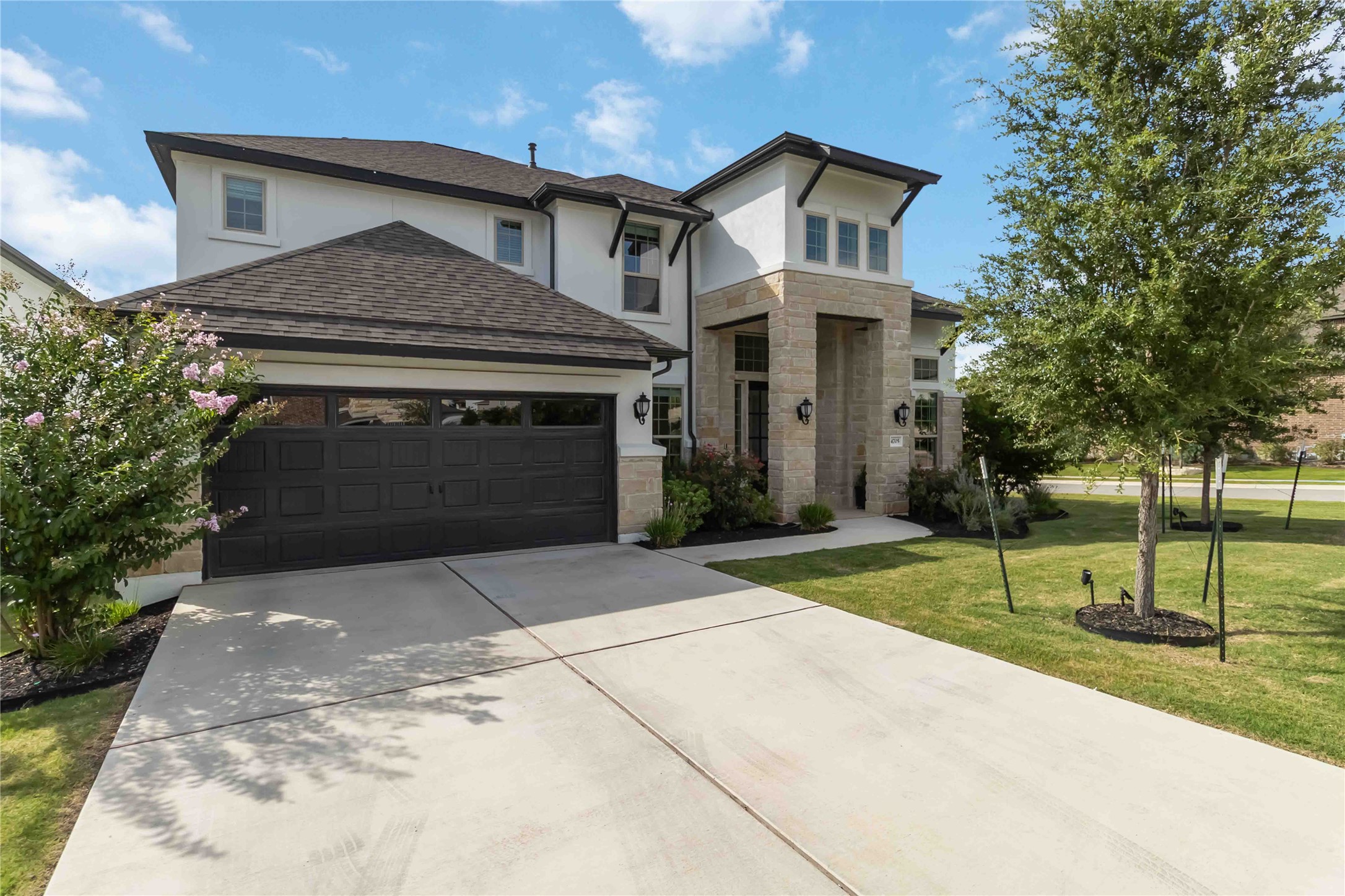 4705 Modena Bay Bend Leander, TX 78641 - Photo 2 of 40 View of front facade featuring a garage, stone siding, stucco siding, and concrete driveway