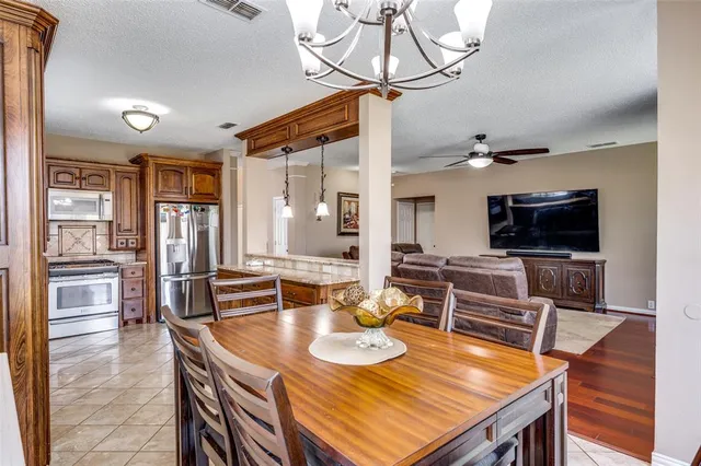a kitchen with a stove a sink dishwasher and a dining table with wooden floor