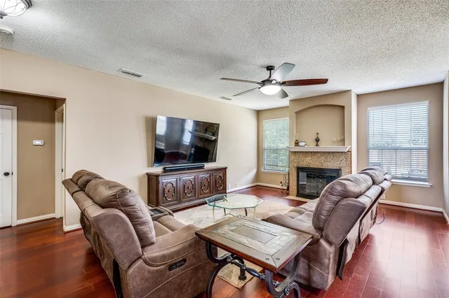 a living room with furniture a fireplace a flat screen tv and wooden floor