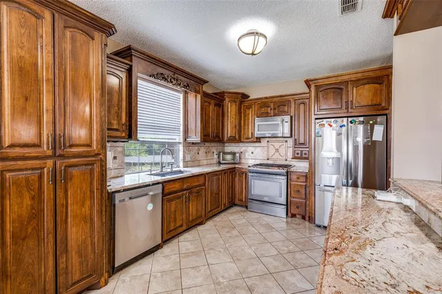 a kitchen with stainless steel appliances granite countertop a refrigerator and a stove top oven