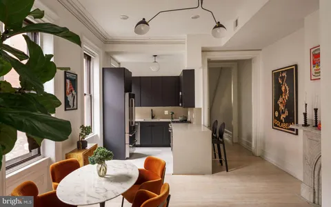 a kitchen with stainless steel appliances a dining table chairs refrigerator and sink