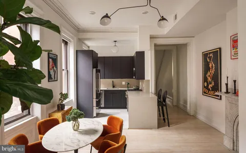 a kitchen with stainless steel appliances a dining table chairs refrigerator and sink