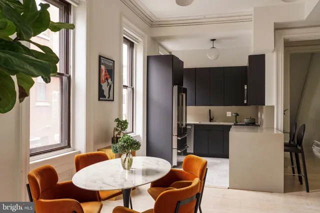 a kitchen with stainless steel appliances a dining table chairs refrigerator and sink