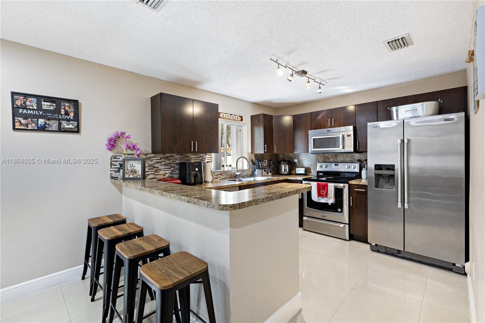 13402 Southwest 153rd Street, Unit 1905 Miami, FL 33177 - Photo 6 of 21 a kitchen with stainless steel appliances granite countertop a refrigerator a stove a sink dishwasher a dining table and chairs with wooden floor