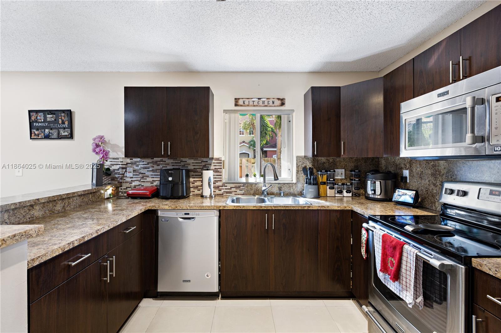 13402 Southwest 153rd Street, Unit 1905 Miami, FL 33177 - Photo 7 of 21 a kitchen with stainless steel appliances granite countertop a stove a sink dishwasher and a microwave oven with wooden cabinets