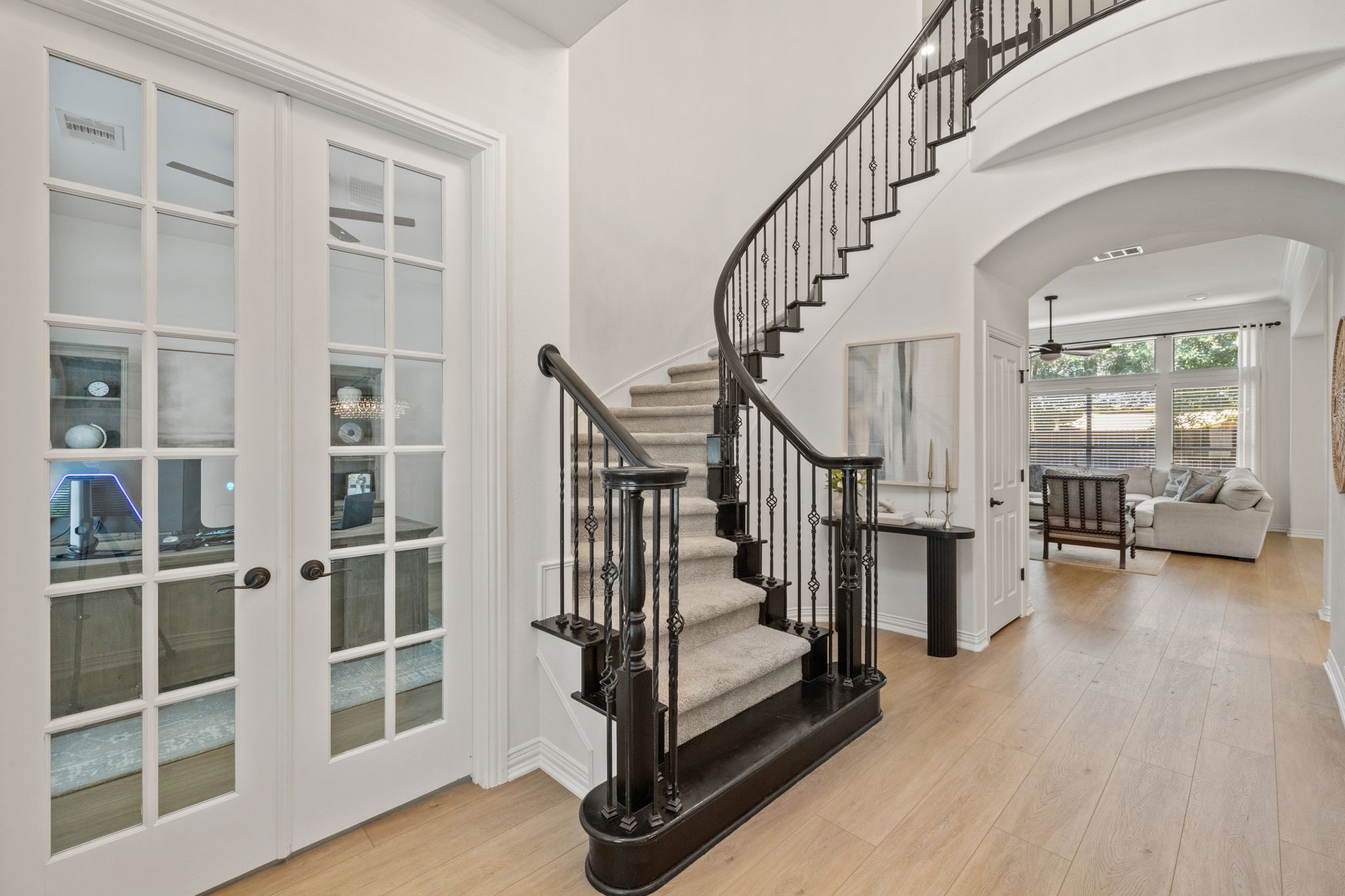 1124 Castle Path Round Rock, TX 78681 - Photo 6 of 40 A grand, curved staircase with ornate iron balusters anchors this elegant entryway, showcasing hardwood floors and french doors.