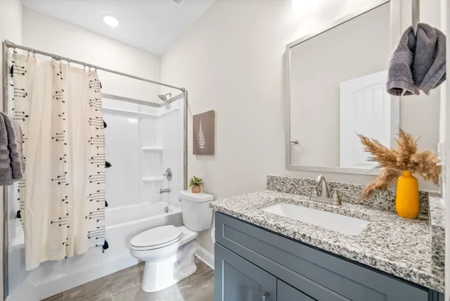a bathroom with a granite countertop sink a toilet and shower