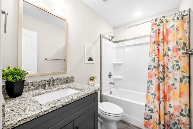a bathroom with a granite countertop sink toilet and shower