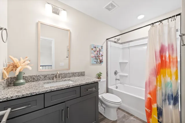 a bathroom with a granite countertop sink toilet and shower