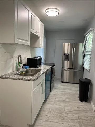 a kitchen with granite countertop a refrigerator and a sink