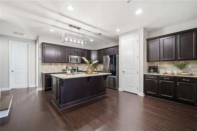 a kitchen with stainless steel appliances kitchen island granite countertop a stove a refrigerator and a wooden floors