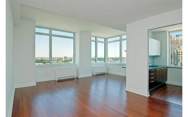 an empty room with wooden floor and windows