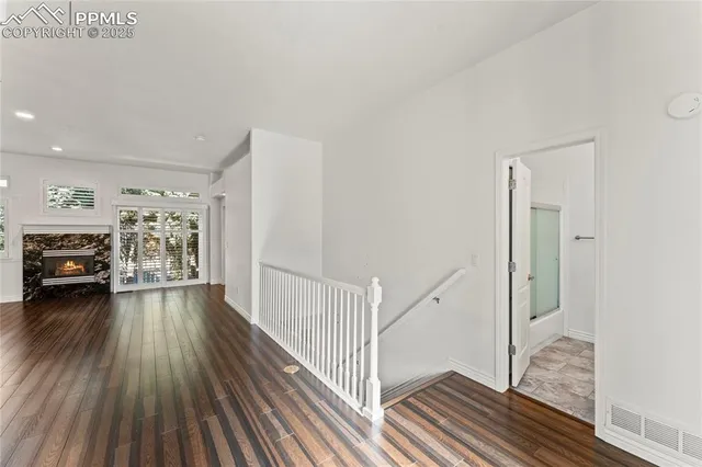 a view of a hallway to an empty room and wooden floor