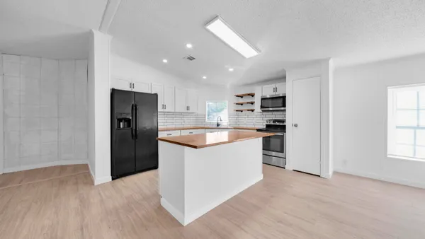 a large kitchen with a center island wooden floor and stainless steel appliances