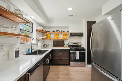 a kitchen with stainless steel appliances granite countertop a sink and a refrigerator