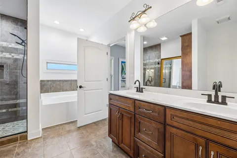 a bathroom with a tub a sink double vanity and a mirror
