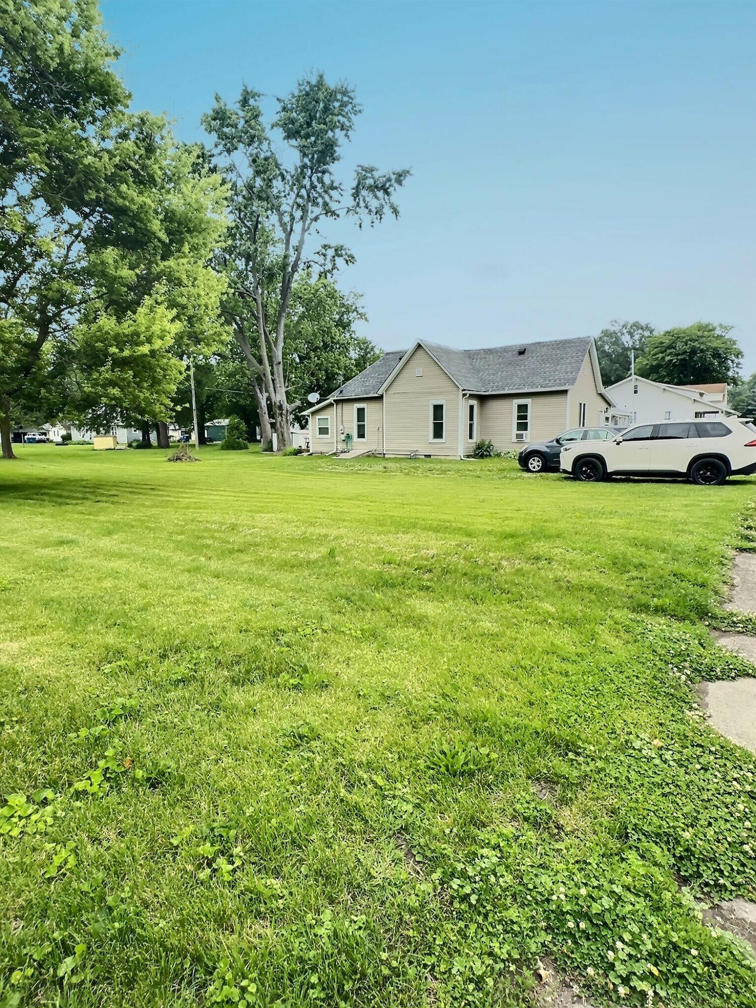 310 West State Street Morocco, IN 47963 - Photo 2 of 17 a view of a house with a big yard potted plants and large tree